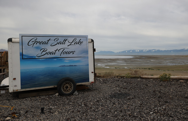 A sign advertising boat tours sits next to a section of the Great Salt Lake that used to be underwater.